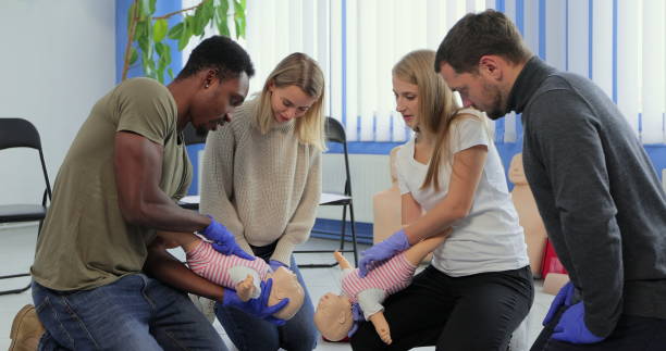 istock Group of multiethnic people during the first aid training with instructor showing on manikin how to do artificial respiration for the baby. 1349671449