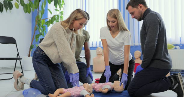 istock Group of people during the first aid training with instructor showing on manikin how to do artificial respiration for the baby. 1349671513