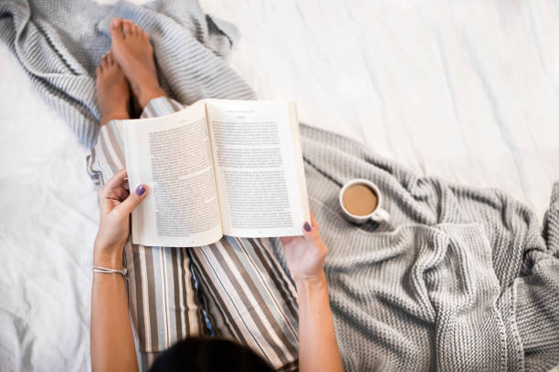 istock Girl reading book and drinking coffee in bed 1349671536