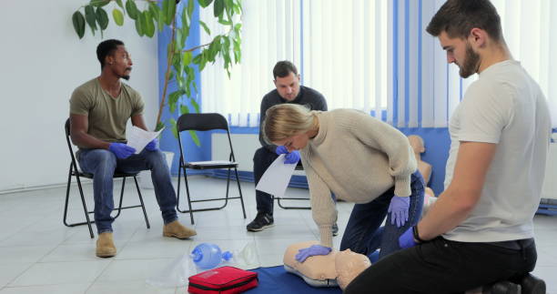 istock Man instructor helping to make first aid heart compressions with teen dummy during the group training indoors. 1349671728