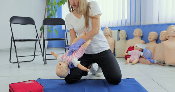 istock Instructor performs CPR on baby training doll. Woman instructor show how to do CPR on a doll dummy for cardiopulmonary reanimation training. 1349672430