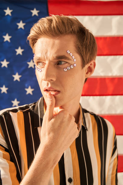 istock Feminine caucasian man looking away tenderly while posing with finger at his lips 1349675294