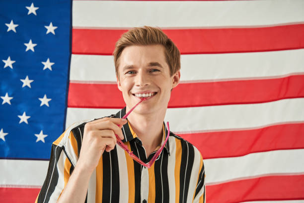istock American citizen smiling toothy while posing with USA flag at the background 1349675295