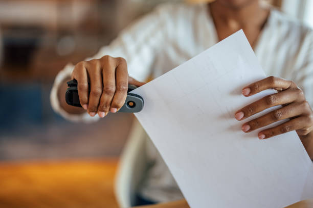 Picture of a woman, putting documents together Picture of a woman, using office appliances for her work stapled paper stock pictures, royalty-free photos & images