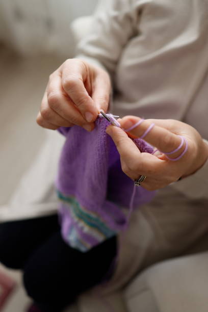 istock Hands of a white middle-aged woman knitting 1349680996