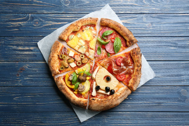 Slices of different pizzas on blue wooden table, top view