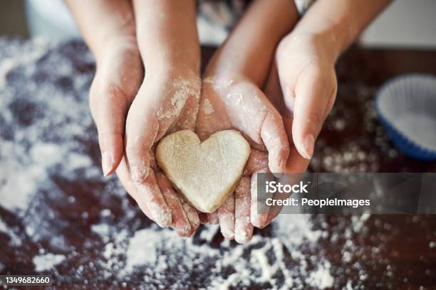 Cropped Shot Of An Unrecognizable Girl And Her Mom Holding A Heart Shaped Cookie In The Kitchen At Home Stock Photo - Download Image Now