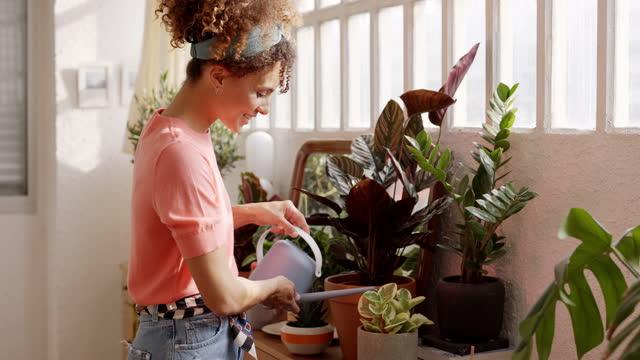 Happy woman watering plants in apartment