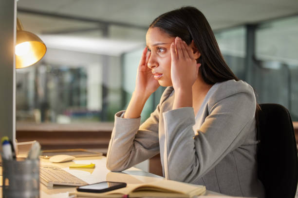 istock Shot of a young businesswoman looking stressed while using a computer at her desk in a modern office 1349682790