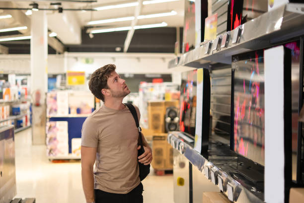 istock Male shopper examining TV on shelf 1349683710