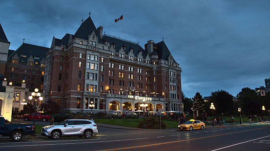 Victoria, British Columbia, Canada - 09-25-2021: Busy street in front of luxury hotel The Fairmont Empress (constructed 1908) in Victoria downtown at Inner Harbour in the evening after sunset.