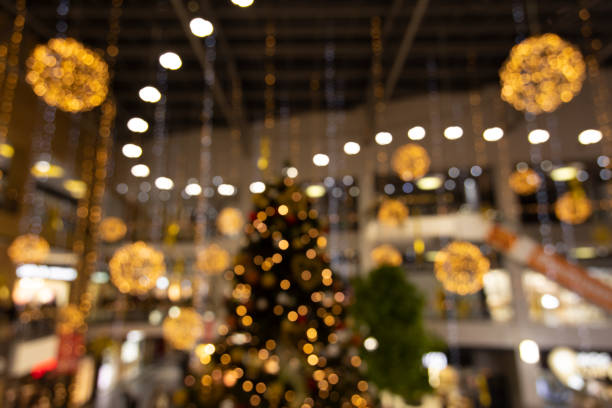 shopping mall preparing for christmas holidays indoor unfocused photography with yellow and golden garland and decoration illuminated objects - christmas shopping imagens e fotografias de stock