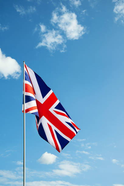 istock Great Britain England  flag waving in the wind over blue sky 1349689379