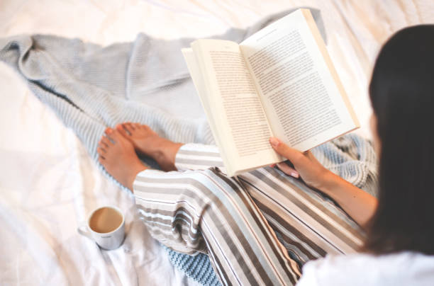 istock Girl reading book and drinking coffee in bed 1349689432