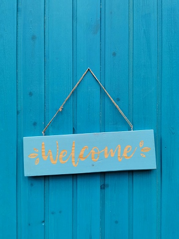The welcome sign on the blue wooden door