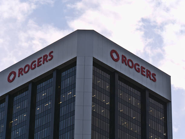 Low angle view of modern office building with glass facade and comapny logo of Rogers Communications Inc. on top on sunny day in autumn with clouds in the sky. stock photo