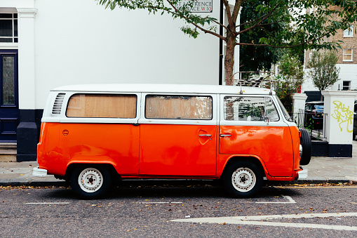 London, UK - 27 October, 2021: vintage Volkswagen Camper van in vibrant orange parked on a residential street in London, UK.