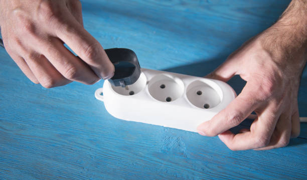 istock Male hands plug electrical plug in extension block. 1349700415