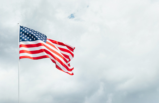 Bandera de Estados Unidos ondeando en el viento sobre el cielo nublado. photo