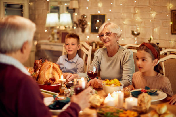 istock Grandparents and grandchildren talking while having Thanksgiving meal at dining table. 1349700815