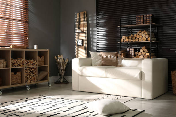 istock Shelving unit with stacked firewood and comfortable sofa in stylish room interior 1349701297