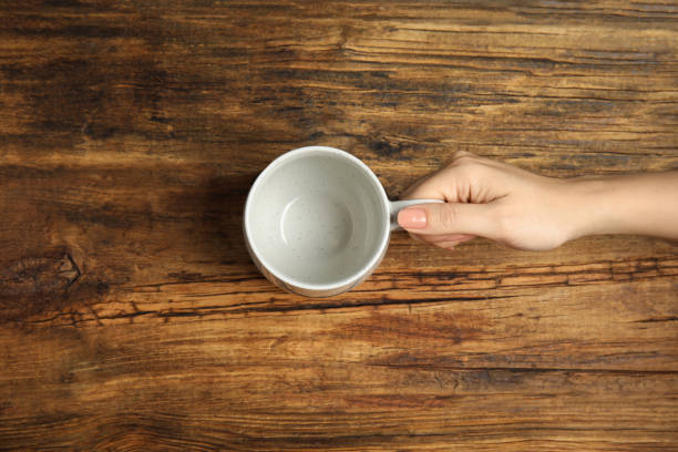 istock Woman with empty cup at wooden table, top view 1349702715