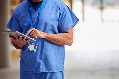 Primer plano de un trabajador médico masculino en exfoliantes con tableta digital en el hospital photo
