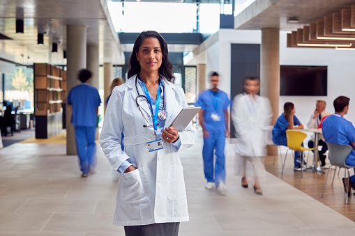 Retrato de una doctora con bata blanca con tableta digital en un hospital ocupado photo