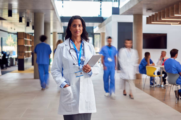 portrait d’une femme médecin portant une blouse blanche avec une tablette numérique dans un hôpital occupé - photography healthcare and medicine horizontal hospital photos et images de collection