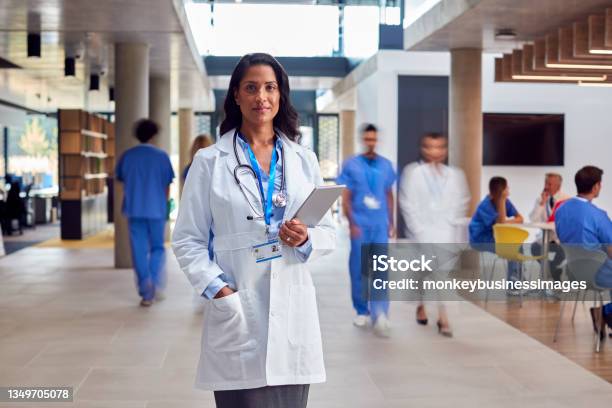 Portrait Of Female Doctor Wearing White Coat With Digital Tablet In Busy Hospital Stock Photo - Download Image Now