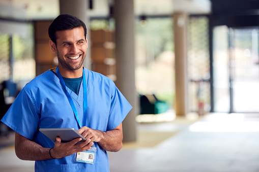 Male Medical Worker In Scrubs With Digital Tablet In Hospital