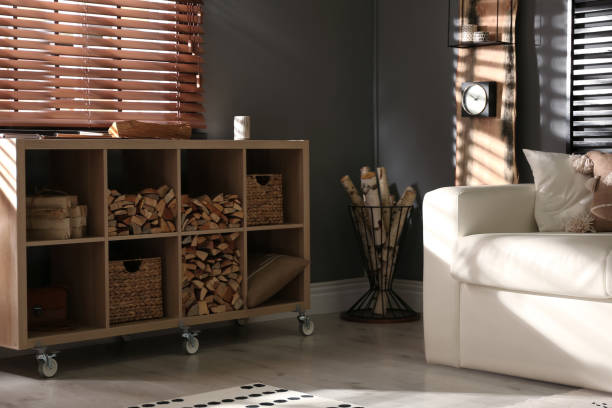 istock Shelving unit with stacked firewood and comfortable sofa in stylish room interior 1349707109
