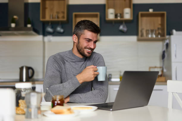 istock Young man doing a video call on his laptop during breakfast 1349708355