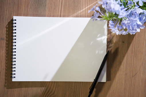 blank sketch book  with flower on wood table top