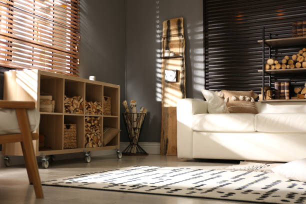 istock Shelving unit with stacked firewood and comfortable sofa in stylish room interior 1349709318