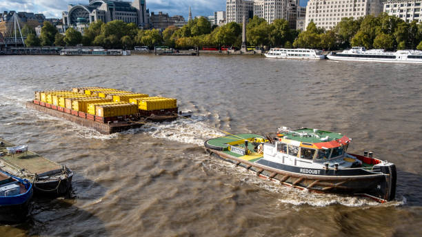 London England UK October 22 2021, Workboat Or Tug Pulling A Barge Carrying Metal Waste Rubbish Containers Along The River Thames In London England UK
