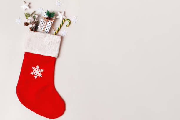 istock Christmas stocking with candy cane gift on light gray background with copy space. 1349710799