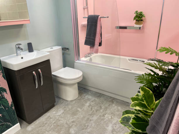 istock Image of modern bathroom with white, ceramic bathtub and glass shower screen, grey vanity unit toped with sink, flush toilet, glossy, grey natural stone floor tiles, grey and pink colour scheme 1349712375