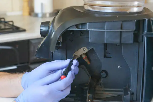 A repairman fixes a broken coffee maker, repair of household appliances