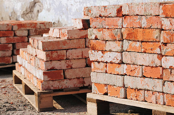Old piles of bricks at a construction site Used bricks placed on pallets. construction material stock pictures, royalty-free photos & images