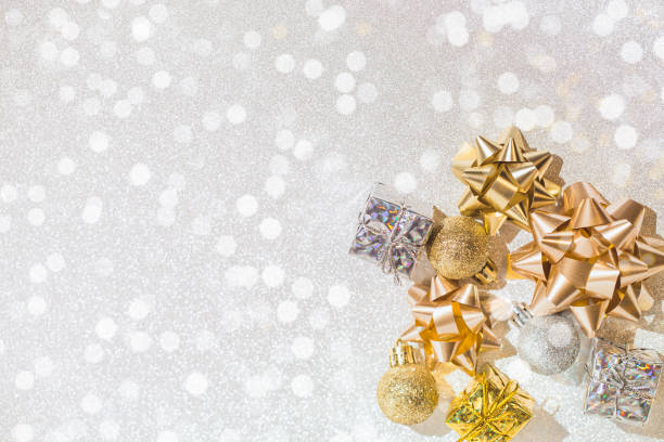 istock Decorative present boxes, balls, golden streamer and decorative bows on white glittering background. 1349715874