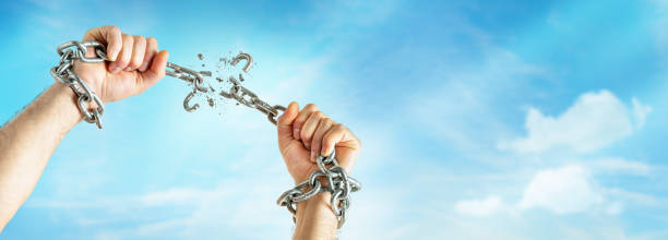 Male hands break the chains Male hands break the chains on clear blue sky background with copy space. Freedom concept. breaking free from chains stock pictures, royalty-free photos & images