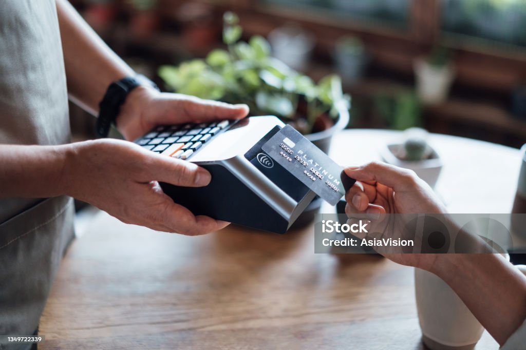 Close up of a woman's hand paying bill with credit card in a cafe, scanning on a card machine. Electronic payment. Banking and technology Credit Card Stock Photo