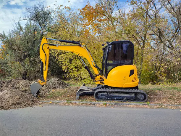 Modern yellow JCB digger or excavator performs excavation work outdoors