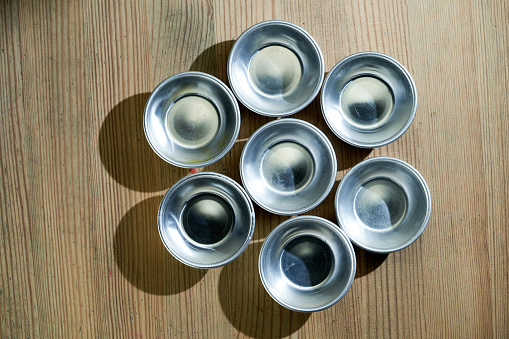 Piles of aluminum dishes and tableware top view on wood background