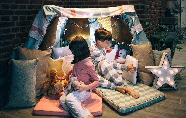 istock Children preparing tent with chairs and bed sheets 1349756577