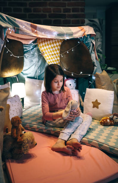 istock Girl in pajamas playing with stuffed bunny in a teepee 1349756578