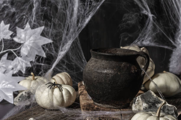 istock Halloween holiday. Festive composition with witch's pot, pumpkins, bat, ghost, spiders, and cobwebs 1349759871