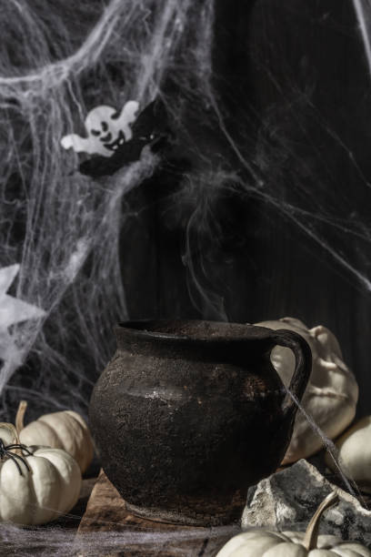 istock Halloween holiday. Festive composition with witch's pot, pumpkins, bat, ghost, spiders, and cobwebs 1349760974