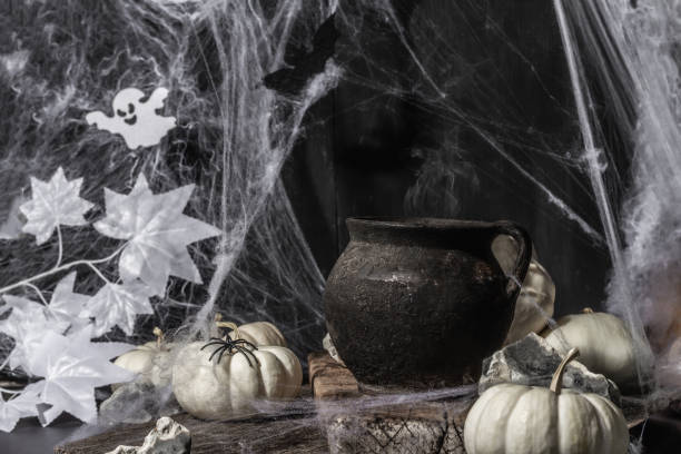 istock Halloween holiday. Festive composition with witch's pot, pumpkins, bat, ghost, spiders, and cobwebs 1349761576